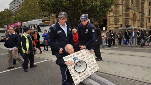 Police remove one of the protesters at today's rally outside Flinders Street Station.