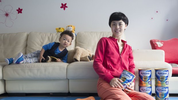 Shanghai resident Cindy Chen, at home with her son and cans of baby milk formula bought from Australia. 