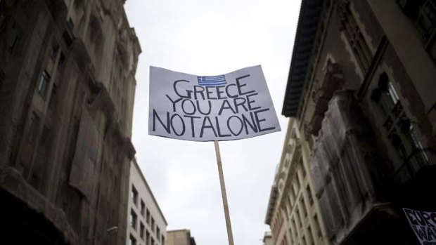 A demonstrator holds up a banner giving support to Greece during a protest against the Euro zone leaders's agreed 'Pact For The Euro' on in Barcelona, Spain.