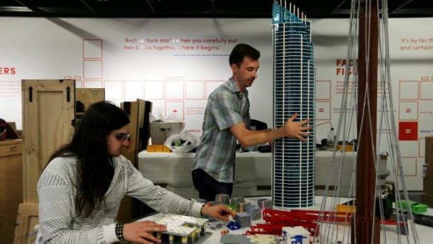 Model builder Ashley Bogar (left) works on the <i>Towers of Tomorrow</i> exhibition with exhibition designer Kieran Larkin. He is holding a replica of the Q1 building from the Gold Coast.