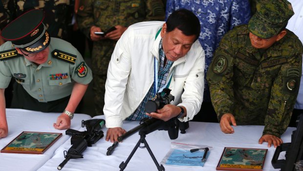 President Rodrigo Duterte checks a Chinese-made sniper's rifle during the presentation of thousands of weapons by China to the Philippines.