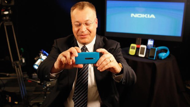 Stephen Elop, chief executive officer of Nokia, holds the new Lumia 800 smartphone during a television interview.