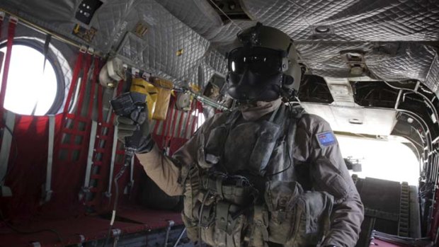 An air crewman from an Australian Army Chinook, based at Kandahar Airfield, uses a control to pick up an American vehicle slung under the aircraft, during a resupply mission to a forward operating base in Afghanistan.