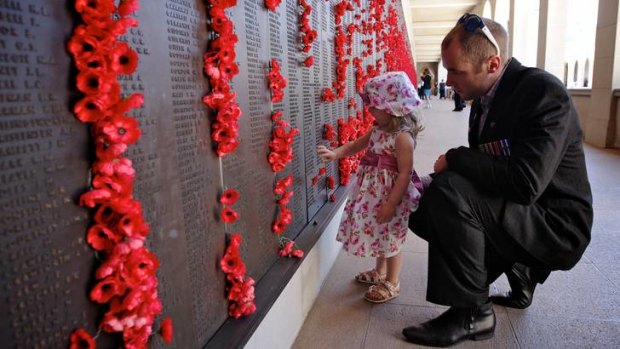Arabella Bailey, 2, and her father, Afghanistan veteran Jamie Bailey, place a poppy on the Roll of Honour at the Remembrance Day ceremony at the Australian War Memorial in Canberra on Sunday.