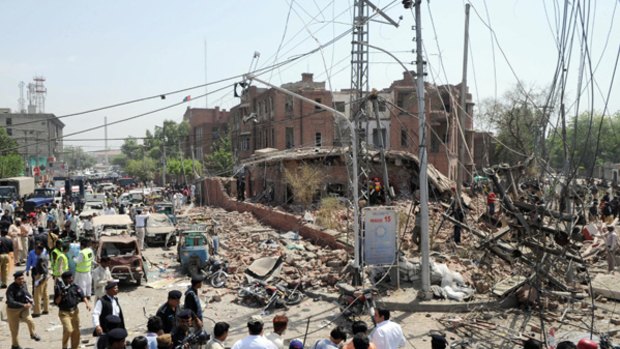 Retaliation ... Pakistani security officials and volunteers gather in front of the destroyed police emergency response office following the suicide car-bomb attack.