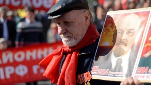 An elderly Russian Communist Party activist carries a portrait of he Soviet Union's founder Vladimir Lenin.