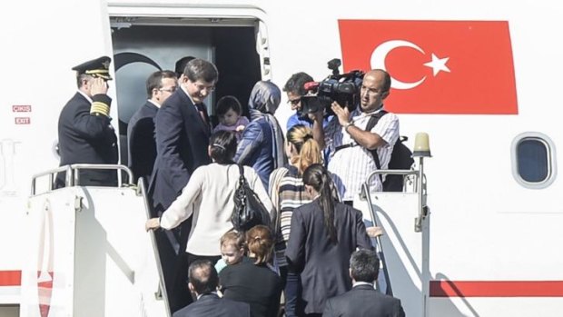 Turkish Prime Minister Ahmet Davutoglu (left) gets into his plane with freed hostages at the airport of the southern Turkish city of Sanliurfa.