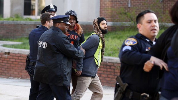 Two marchers are detained by Baltimore police after they climbed over the barricades guarding the department's Western District police station during a march for Freddie Gray.