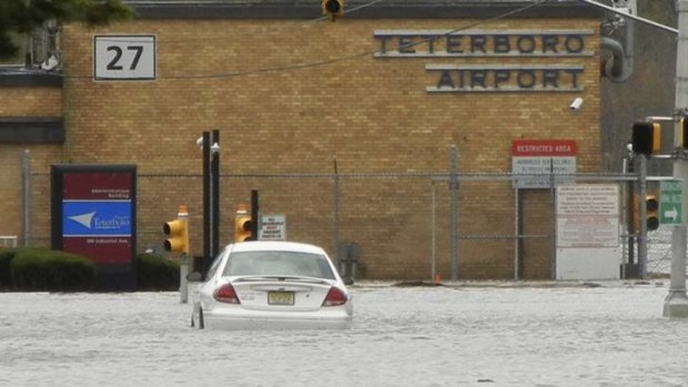 A car is partially submerged in flood waters on road leading to Teterboro Airport in Teterboro, New Jersey.