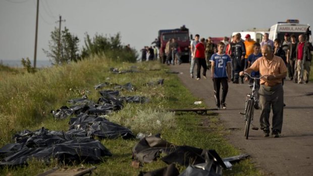 Pleas to bring them home: The bodies of victims are placed by the side of the road near the crash site.