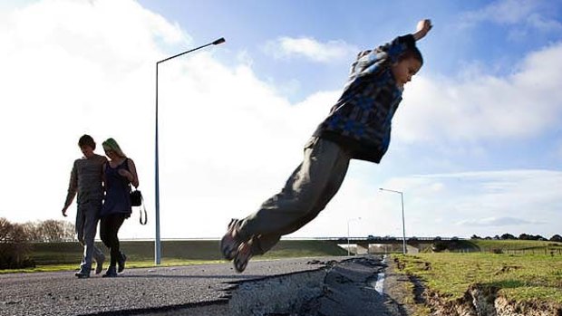 Mind the gap ... Tia Carranceja leaps a section of the damaged Highway No.1 in the north of Christchurch.