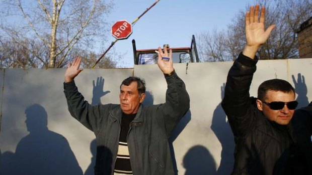 Pro-Russian protesters hold their hands up in the air in Kramatorsk.