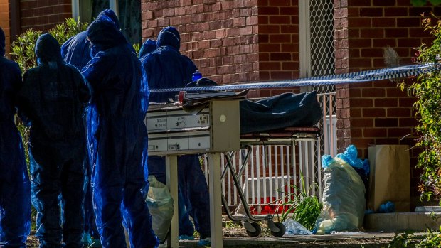 ACT police officers remove a dead body from a block of flats in Windeyer street Watson.