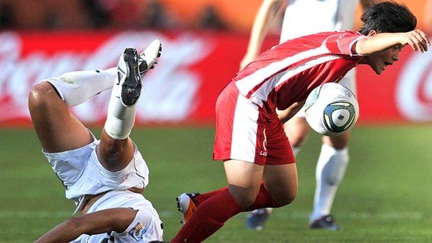 USA's midfielder Carli Lloyd slams into the turf as North Korea's midfielder Kim Su Gyong escapes with possession.