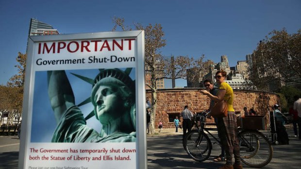 People look at a sign informing them that the Statue of Liberty is closed due to the government shutdown in Battery Park, New York.