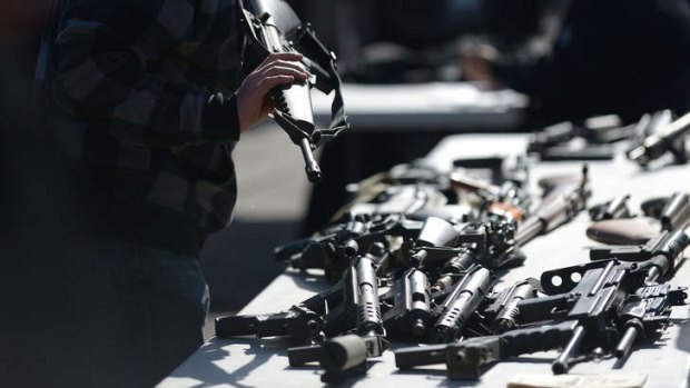 A police officer checks one of 16 assault weapons received.