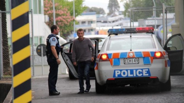 In custody: Phil Rudd, 60, dressed in jeans and a grey sweater, gets out of a police car.