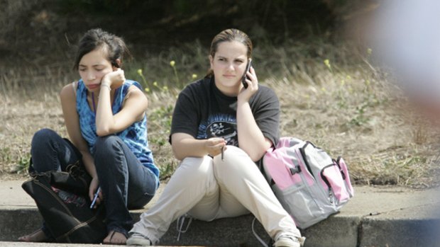 Shooting ... two students wait off campus after they were evacuated at Skyline College in San Bruno, California.