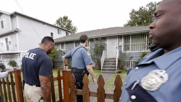 Seattle police officers walk towards a house where Aaron Alexis  lived  in 2004 and 2005.
