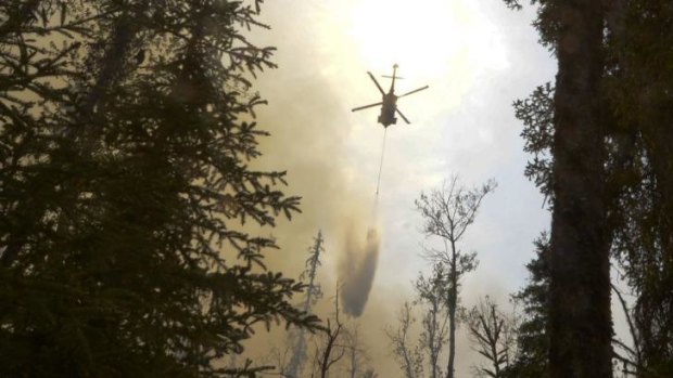 A helicopter dumps water on a portion of the Funny River fire in Alaska