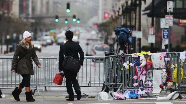 Crime scene: People walk past a barricade and makeshift memorial blocking a still closed section of Boylston Street near the site of the Boston Marathon bombings.