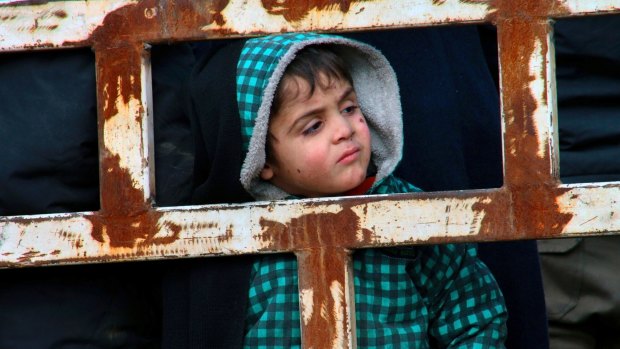 A boy from eastern Aleppo stands in the back of a truck with his family after being evacuated.