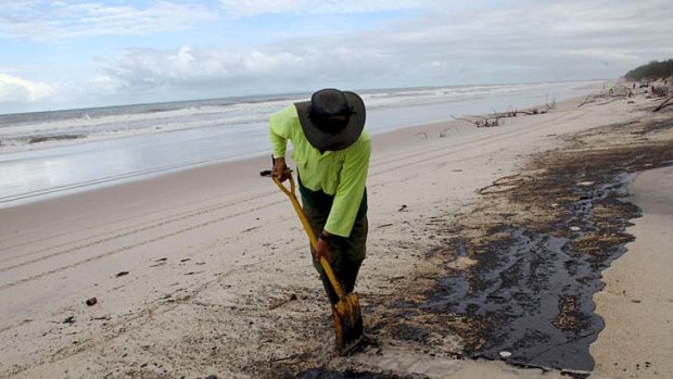 A clean-up worker removes oil from Bribie Island after the 2009 spill.