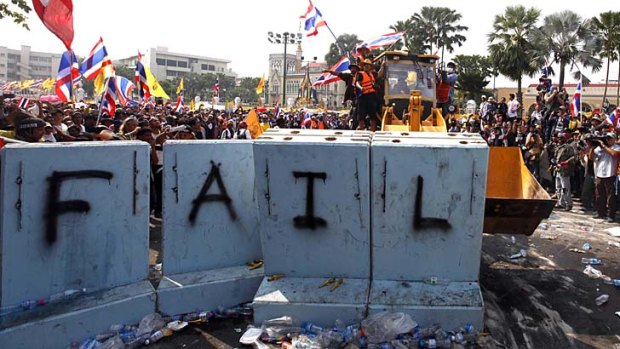 Protesters use a front loader to knock down a concrete barricade outside the Government House in the country's capital.