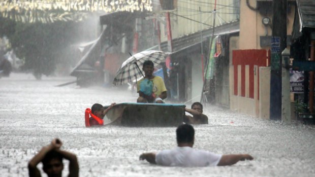 Aftermath: Manila residents wade through a flooded street.