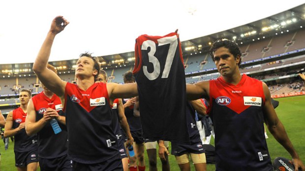 Melbourne captain James McDonald and Aaron Davey carry the jumper of club president Jim Stynes last July.