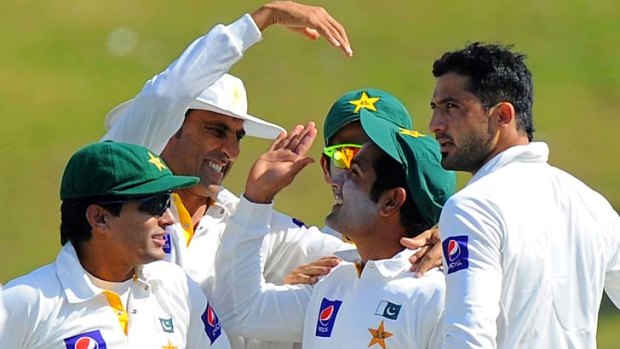 Pakistan's Younis Khan (second left), Asad Shafiq (second right), and bowler Junaid Khan (right) celebrate after the dismissal of Sri Lankan batsman Dimuth Karunaratne on the opening day of the first Test in Abu Dhabi on Tuesday.