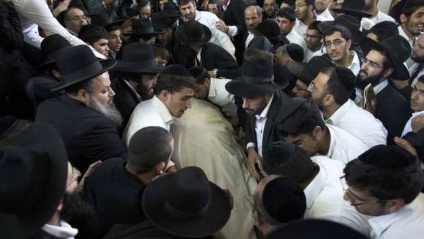 Ultra-Orthodox Jewish men gather near the body of Rabbi Ovadia Yosef.