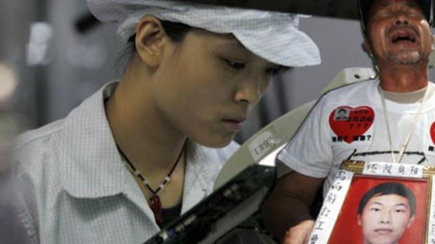 Focus ... a Foxconn staff member works on the production line at the company complex near Shenzhen. Right, Ma Zishan carries a picture of his dead son.