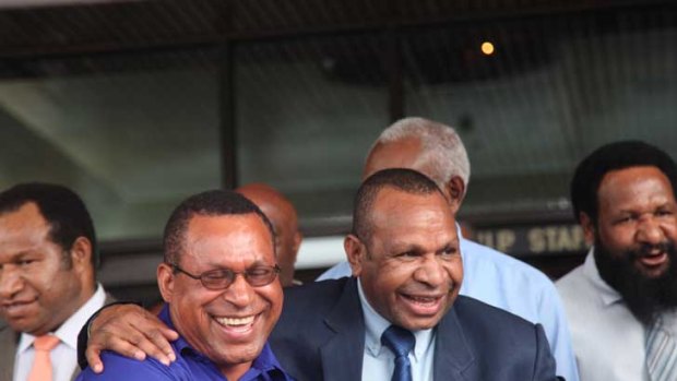 Sir Michael supporter MP Philemon Embel, a minister in Somare's cabinet, shares a joke and laugh with Peter O'Neill's deputy prime minister Beldan Namah outside government offices today.