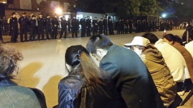 Family members of passengers aboard missing Malaysia Airlines Flight MH370 gather for a sit-in protest as security personnel stand guard outside the Malaysian embassy in Beijing.