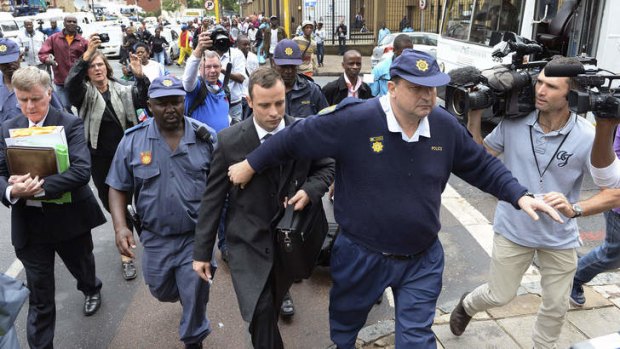 The crowd continues to grow: Oscar Pistorius is escorted outside the court in Pretoria.