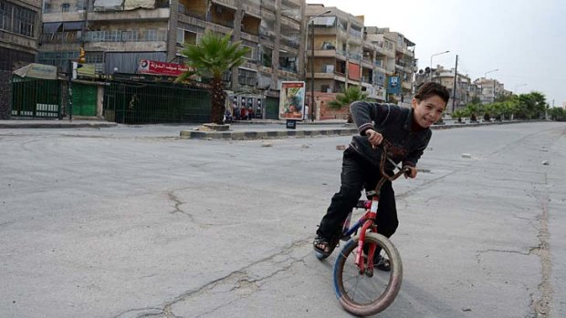 A Syrian child rides his bicycle along a deserted street in Aleppo.