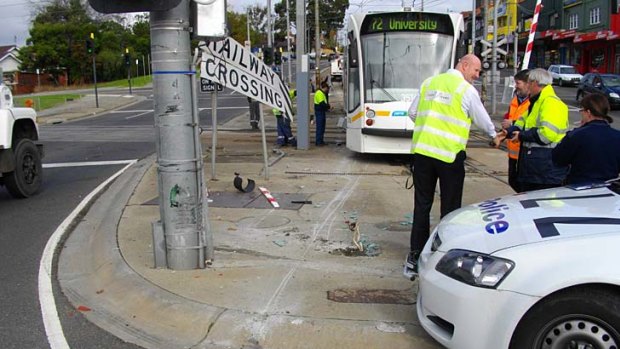 A derailed tram sits astride the railway line at the level crossing on Burke Road, Glen Iris.