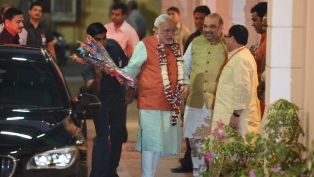 On his way: Indian Prime Minister Narendra Modi (in orange) arrives at the headquarters of the ruling BJP in Delhi on Saturday.