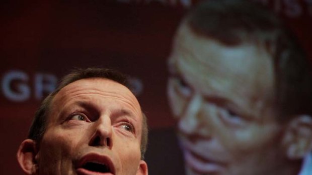 Not budging on asylum seekers ... Tony Abbott, beneath a big-screen image of himself, addresses industry leaders at Parliament House yesterday.