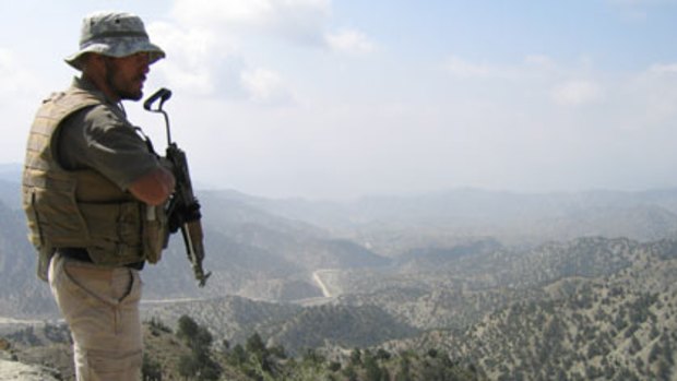 Dangerous work...(left) a Romanian security contractor stands guard at a section of the road from Khost to Gardez.