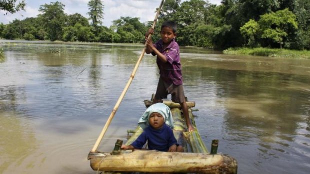 A boy rows a makeshift raft carrying a child through the flooded areas of Lakhimpur district in the north-eastern Indian state of Assam.
