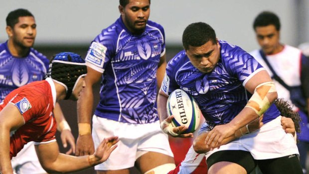 Sakaria Taulafo of Samoa runs through a tackle by  Viliami Faingaa of Tonga.
