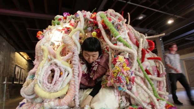 Art imitating life ... Hiromi Tango, who is eight months pregnant, with her portable womb, made from materials including plastic flowers and dolls for the Primavera exhibition.