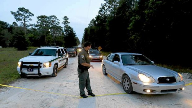 An officer lowers police tape to let cars through at the scene of the shooting in Bell, Florida.