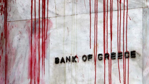 A branch of the Bank of Greece is seen stained with red paint thrown by demonstrators during a protest in central Athens.