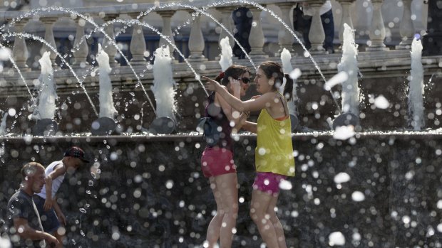 Girls cool off in a fountain  in Alexandrov Garden at the Kremlin Wall in Moscow, Russia on July 30, 2014.