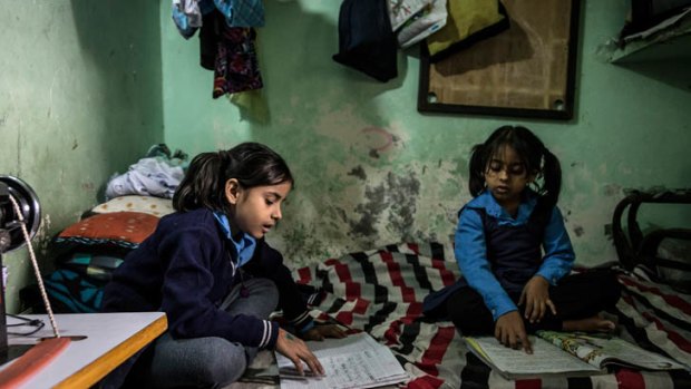 Farha Khan, seven, (at left) studies in the tiny one room family home in Govindpuri she shares with her parents and six-year-old sister Farhana.