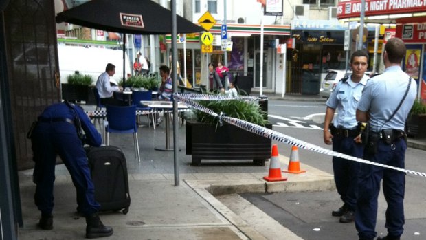 Police examine the bag that was found stuffed full of money at a Sydney cafe.