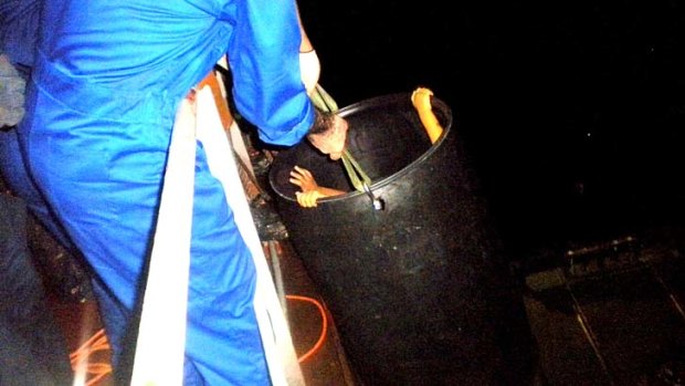 Children being rescued from the boat using a bucket.